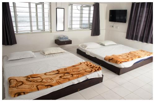 une chambre avec deux lits et une télévision à écran plat dans l'établissement Mubeen beach villa, à Pondichéry
