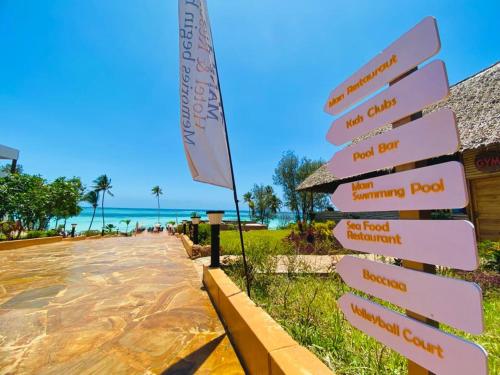 a directional sign at the beach with the ocean in the background at Royal Mandarin Hotel & Resort in Pwani Mchangani