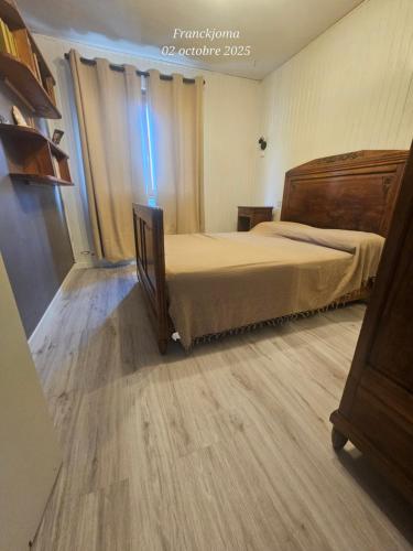 Un dormitorio con una cama y suelo de madera. en Appartement à 5min du centre ville d'Embrun, en Embrun