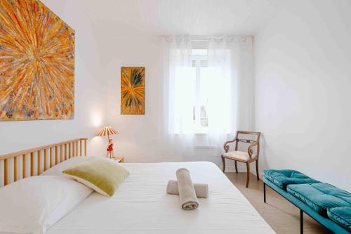 a bedroom with a large white bed and a chair at Les coques bleues in Granville