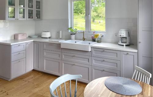 a kitchen with white cabinets and a sink and a table at Nice Home In Edsbruk With Kitchen in Edsbruk