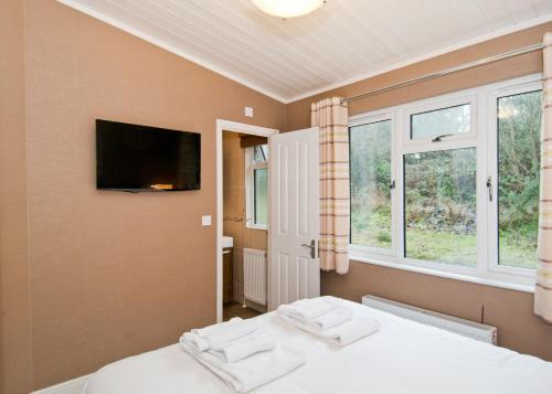 a bedroom with a bed and a tv on the wall at Warren Lodges in Little Baddow