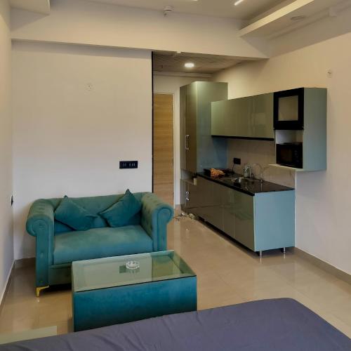 a living room with a blue couch and a kitchen at Kremlin Luxury Studios in Ghaziabad