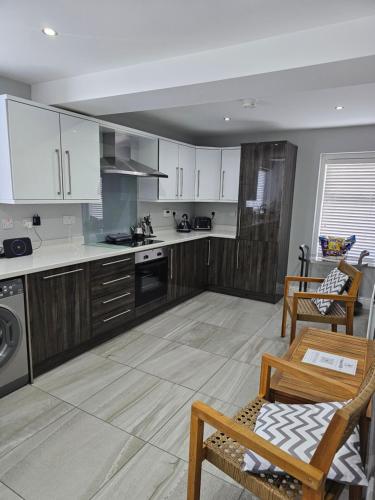 a kitchen with white cabinets and a table and chairs at Atlantic Sea View in Portstewart