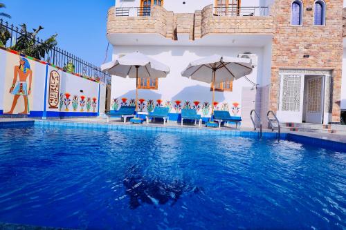 a swimming pool with chairs and umbrellas in a building at SunWing guest house in Luxor