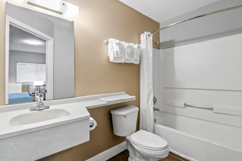 a bathroom with a sink and a toilet and a mirror at Suburban Studios Stuart near Federal Hwy 1 in Stuart