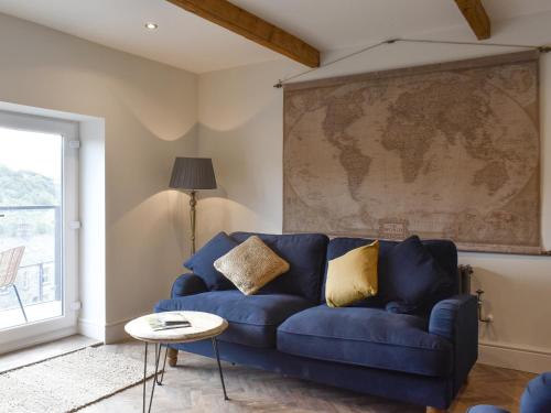 a blue couch in a living room with a map on the wall at Seamstress Cottage in Ripponden