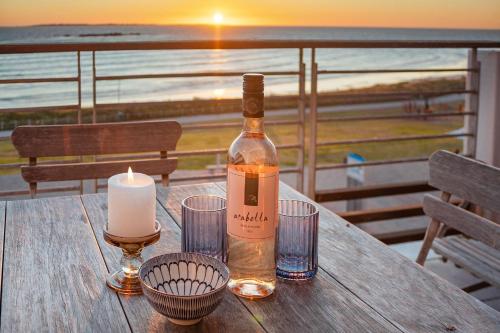 a bottle of wine sitting on a table with a candle at Eden on The Bay 250 in Bloubergstrand