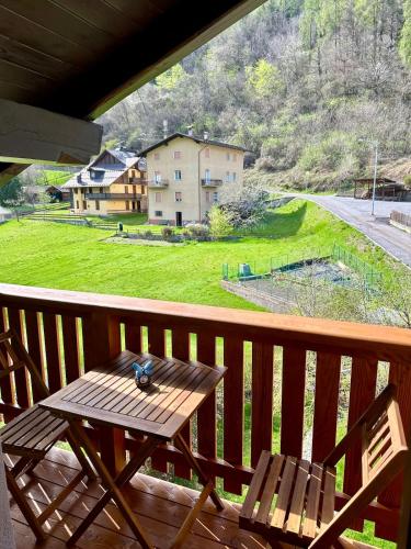 a wooden table on a porch with a view of a house at Val di Sole Apartment in Monclassico