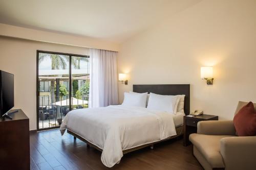 a bedroom with a bed and a living room with a couch at Fiesta Inn Oaxaca in Oaxaca City