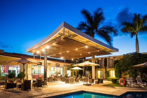 a patio with a pool and tables and umbrellas at Fiesta Inn Oaxaca in Oaxaca City