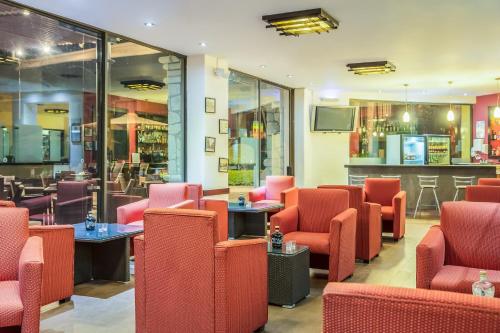 a restaurant with red chairs and a bar at Fiesta Inn Oaxaca in Oaxaca City