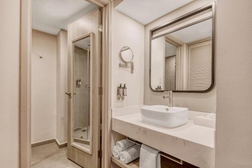 a white bathroom with a sink and a mirror at Fiesta Inn Oaxaca in Oaxaca City