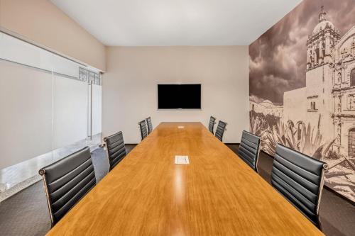 a conference room with a long wooden table and chairs at Fiesta Inn Oaxaca in Oaxaca City