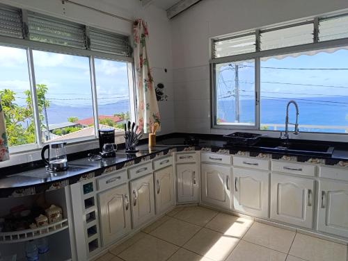 - une cuisine avec des placards blancs et de grandes fenêtres dans l'établissement Villa mangue Julie, à Trois-Rivières