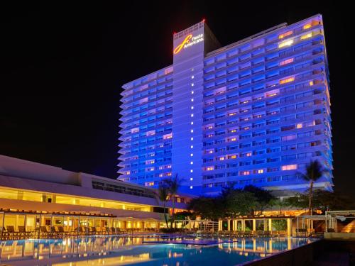 a lit up building with a pool in front of it at Fiesta Americana Acapulco Villas in Acapulco