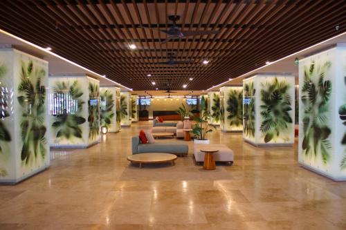 a lobby with couches and palm trees on the walls at Fiesta Americana Acapulco Villas in Acapulco