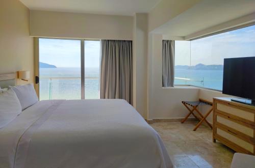 a bedroom with a large bed and a large window at Fiesta Americana Acapulco Villas in Acapulco