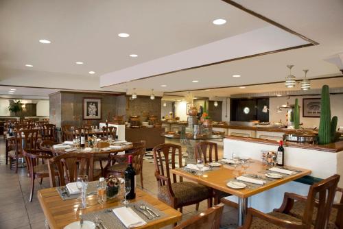 a restaurant with wooden tables and chairs and a bar at Fiesta Americana Reforma in Mexico City