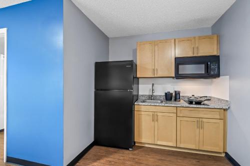 a kitchen with a black refrigerator and wooden cabinets at Suburban Studios Stuart near Federal Hwy 1 in Stuart