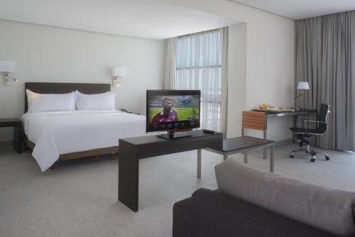 a hotel room with a bed and a flat screen tv at Fiesta Inn Monterrey Fundidora in Monterrey