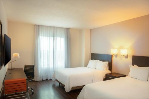 a hotel room with two beds and a window at Fiesta Inn Monterrey Fundidora in Monterrey