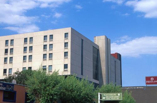 a building on a city street with a blue sky at Fiesta Inn Tlalnepantla in Mexico City