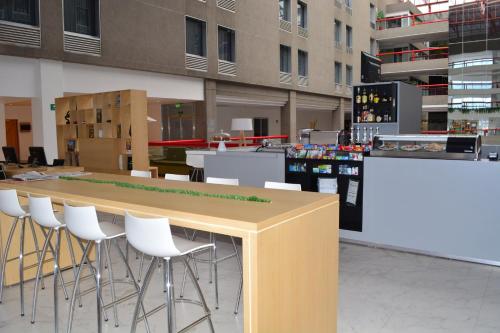 a bar with white bar stools in a building at Fiesta Inn Tlalnepantla in Mexico City
