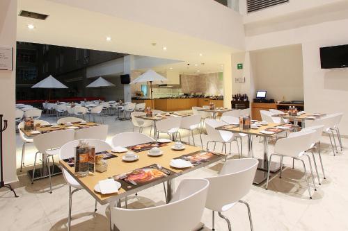 a dining room with tables and white chairs at Fiesta Inn Tlalnepantla in Mexico City