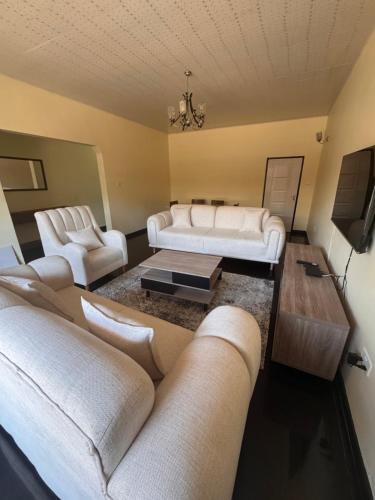 sala de estar con sofás blancos y TV en Cn PROPERTIES, en Lusaka