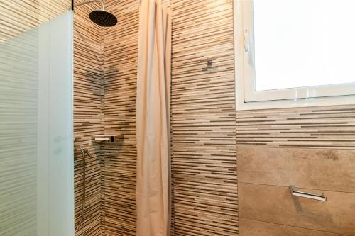 a shower in a bathroom with a wooden wall at ACROPOLIS CASA Historic Centre Top Floor Elegant Stylish Retreat 150m to Metro & Attractions in Athens