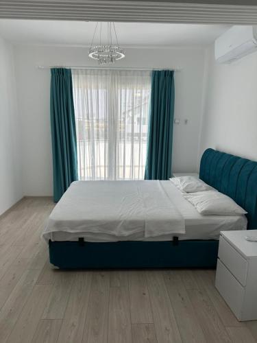 a bedroom with a bed with a blue headboard and a window at Glapsides Sea Villa in Famagusta