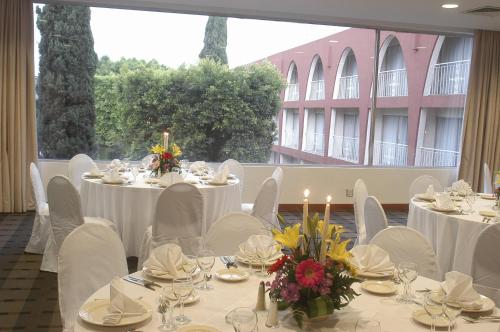 a dining room with white tables and chairs and a large window at Fiesta Inn Ciudad de México Aeropuerto in Mexico City