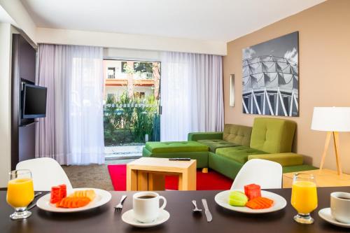 a living room with a table and a green couch at Fiesta Inn Ciudad de México Aeropuerto in Mexico City
