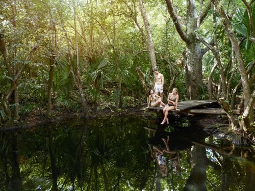 three people sitting on a bridge over a body of water at The Explorean Cozumel All Inclusive in Cozumel