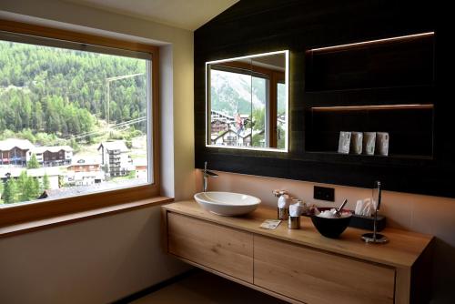 Un baño con lavabo y una gran ventana. en The Dom Hotel Saas-Fee operated by Dorint, en Urnäsch