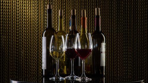 four wine glasses sitting on a table with wine bottles at Grand Fiesta Americana Chapultepec in Mexico City