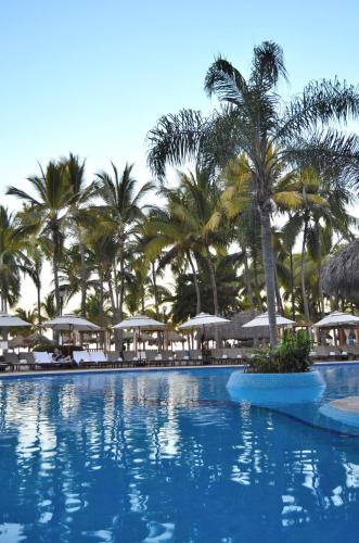 a large swimming pool with palm trees and umbrellas at Fiesta Americana Puerto Vallarta All Inclusive & Spa in Puerto Vallarta