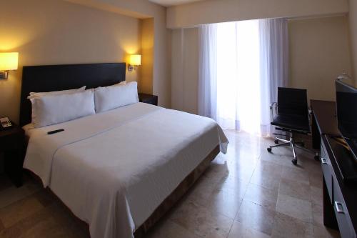 a bedroom with a large white bed and a television at Fiesta Inn Coatzacoalcos in Coatzacoalcos