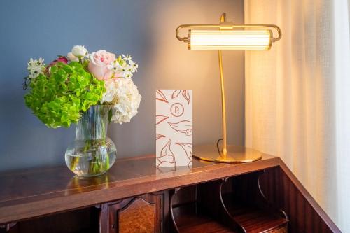 a table with a vase of flowers and a lamp at Pergola Boutique Hotel in Cascais