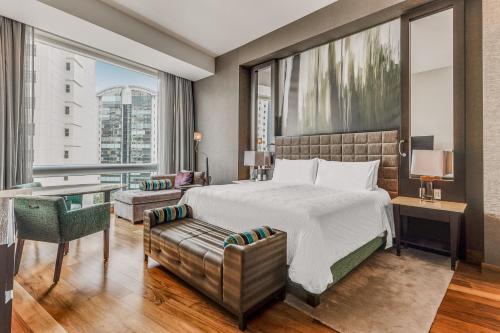 a bedroom with a bed and a desk and a large window at Live Aqua Ciudad de Mexico Bosques de las Lomas in Mexico City