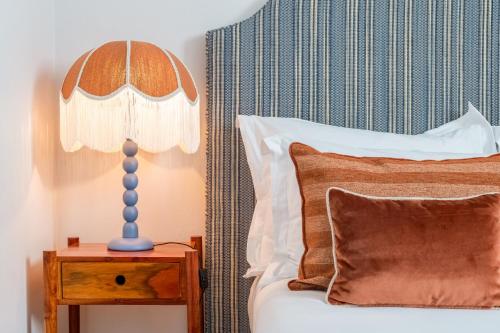 a bed with a lamp on a table next to it at Pergola Boutique Hotel in Cascais