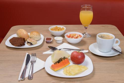 a table with plates of food and a glass of orange juice at ibis Manaus Aeroporto in Manaus