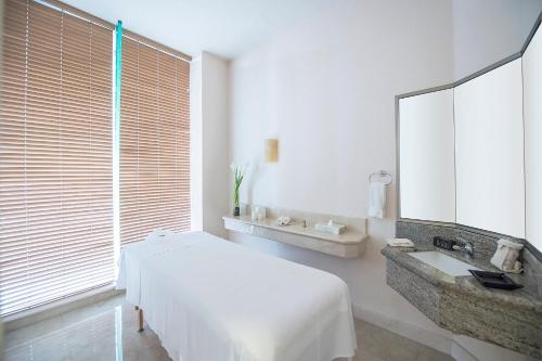 a bedroom with a bed and a sink and a mirror at Grand Fiesta Americana Guadalajara Country Club in Guadalajara