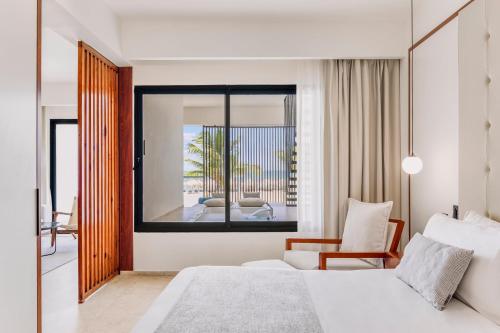 a bedroom with a bed and a chair and a mirror at Live Aqua Punta Cana - All Inclusive - Adults Only in Punta Cana