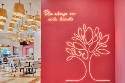 a red wall with a tree painted on it at Fiesta Inn Cuernavaca in Cuernavaca