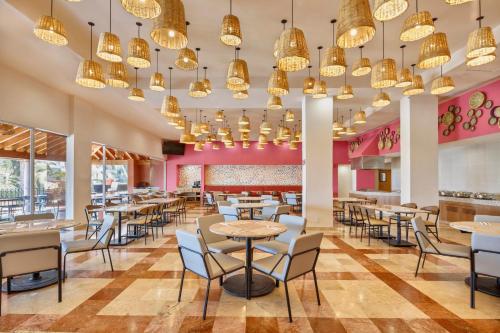 a dining room with tables and chairs and chandeliers at Fiesta Inn Cuernavaca in Cuernavaca