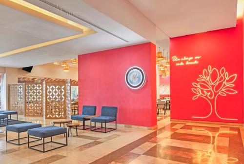 a waiting room with blue chairs and a red wall at Fiesta Inn Cuernavaca in Cuernavaca