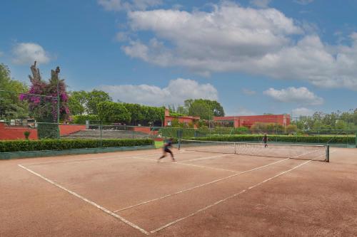 two people playing tennis on a tennis court at Fiesta Americana Hacienda Galindo Resort & Spa in Galindo