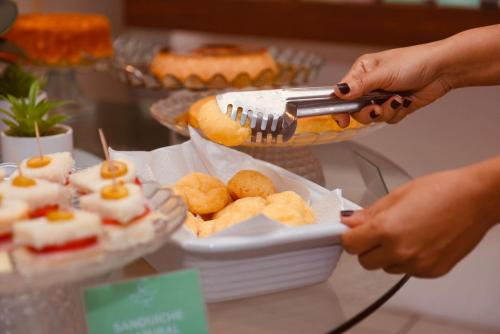 eine Person serviert Essen auf einem Buffet-Tisch in der Unterkunft Hotel Village in Garanhuns